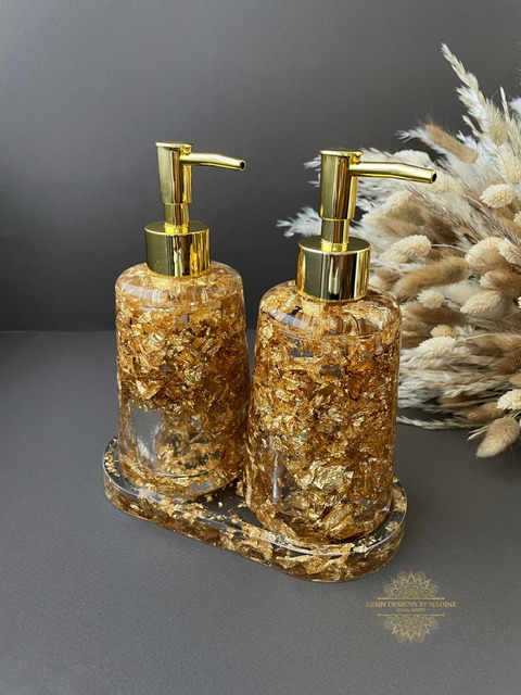 Two gold soap dispensers with gold pumps